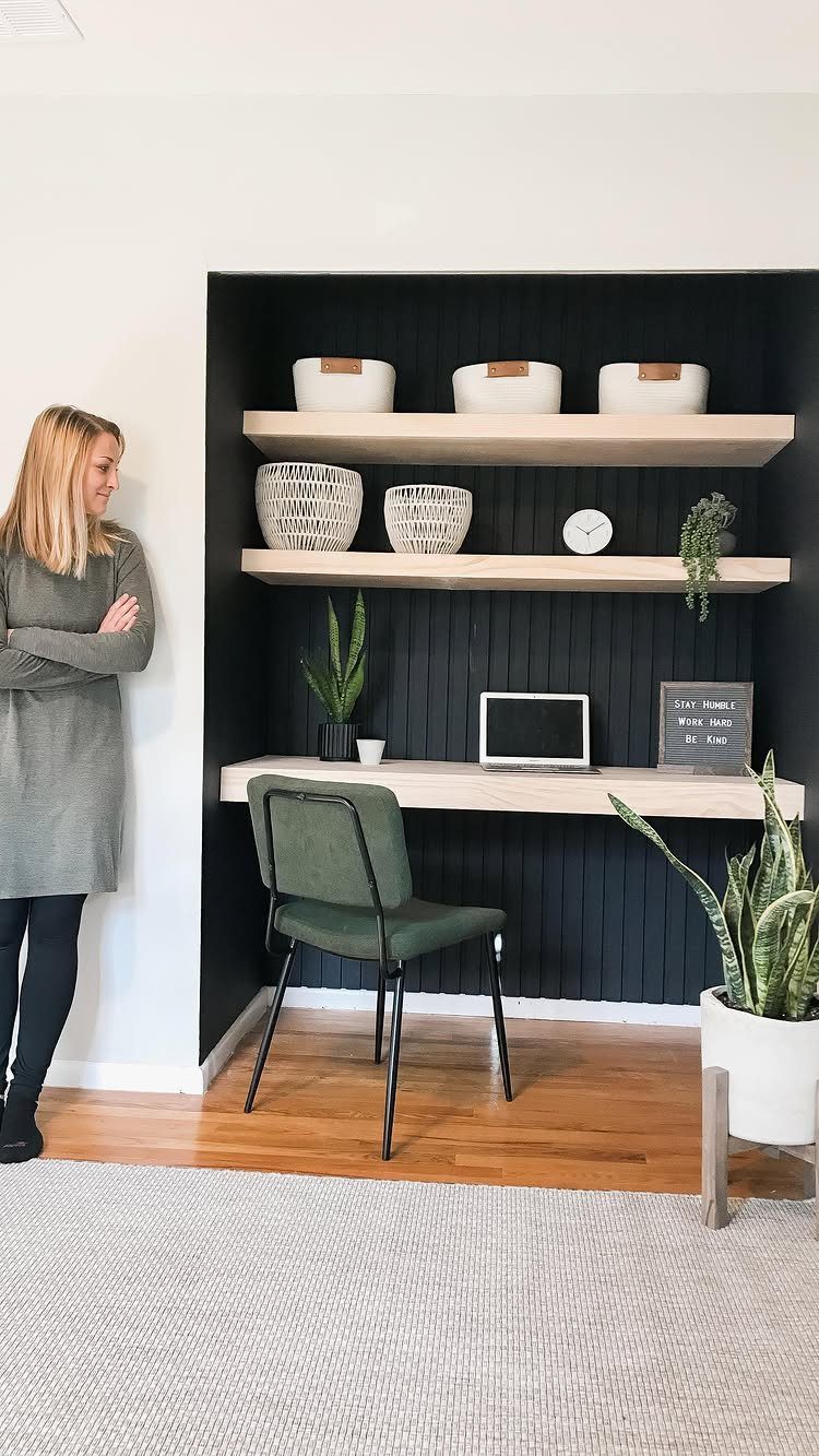 Small home office built into a wall niche with navy slatted walls and floating shelves.
