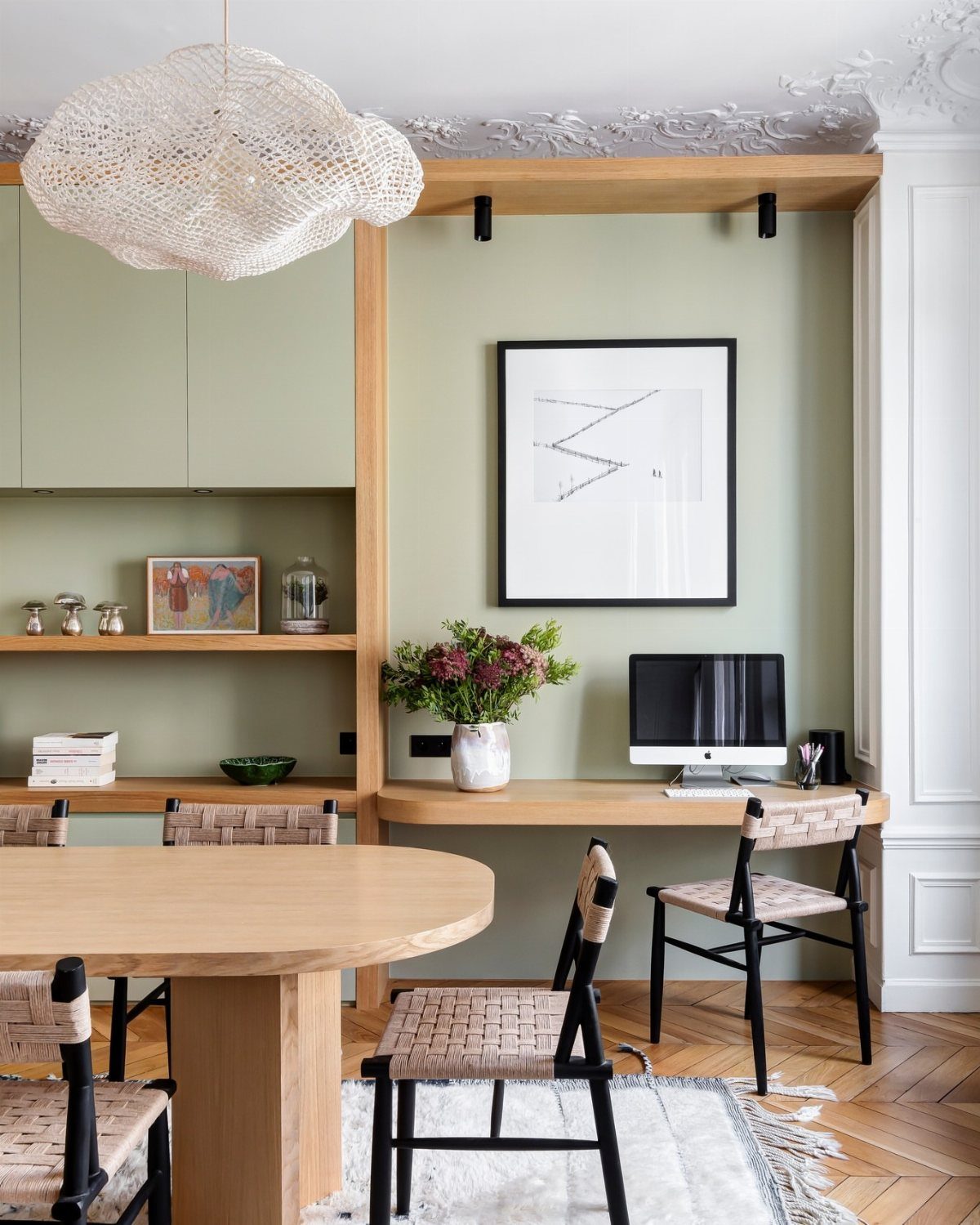 Light wood desk in a green wall niche with a computer and chair.