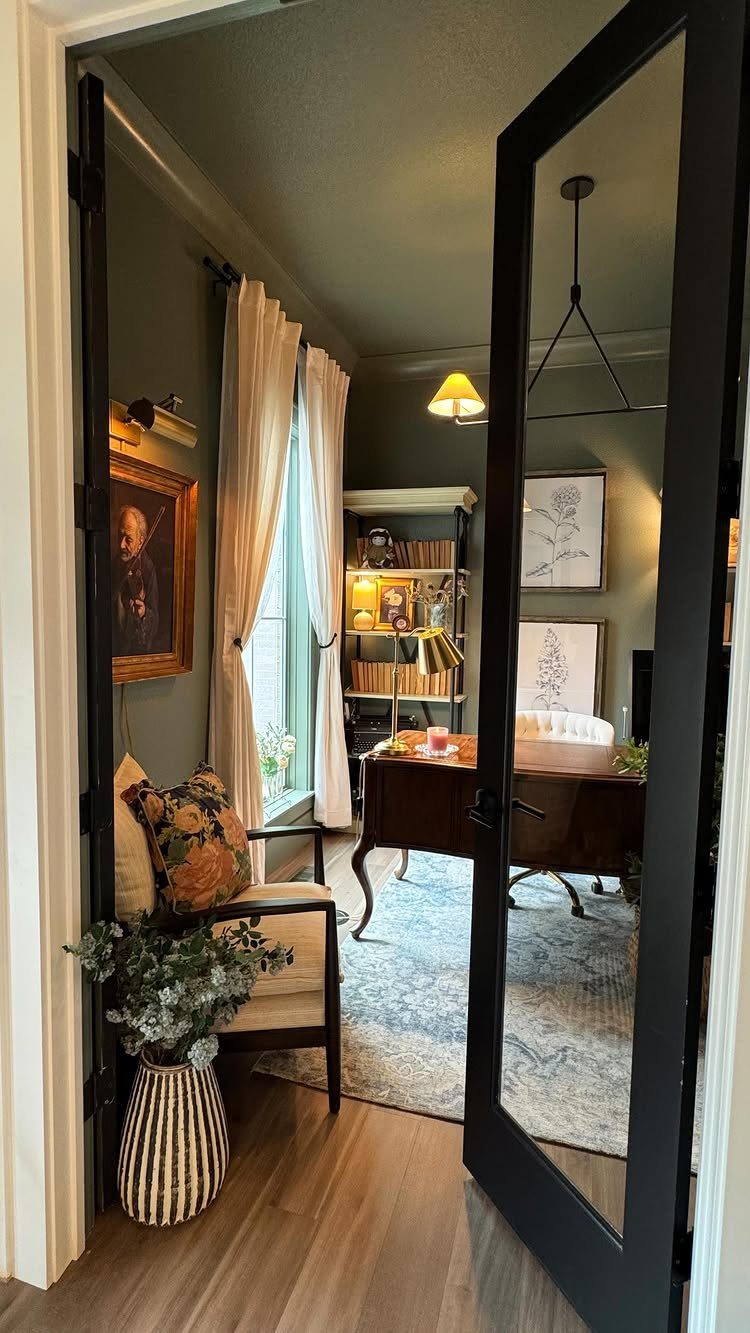 Vintage home office with a dark wood desk, gold-framed portrait, and olive walls.