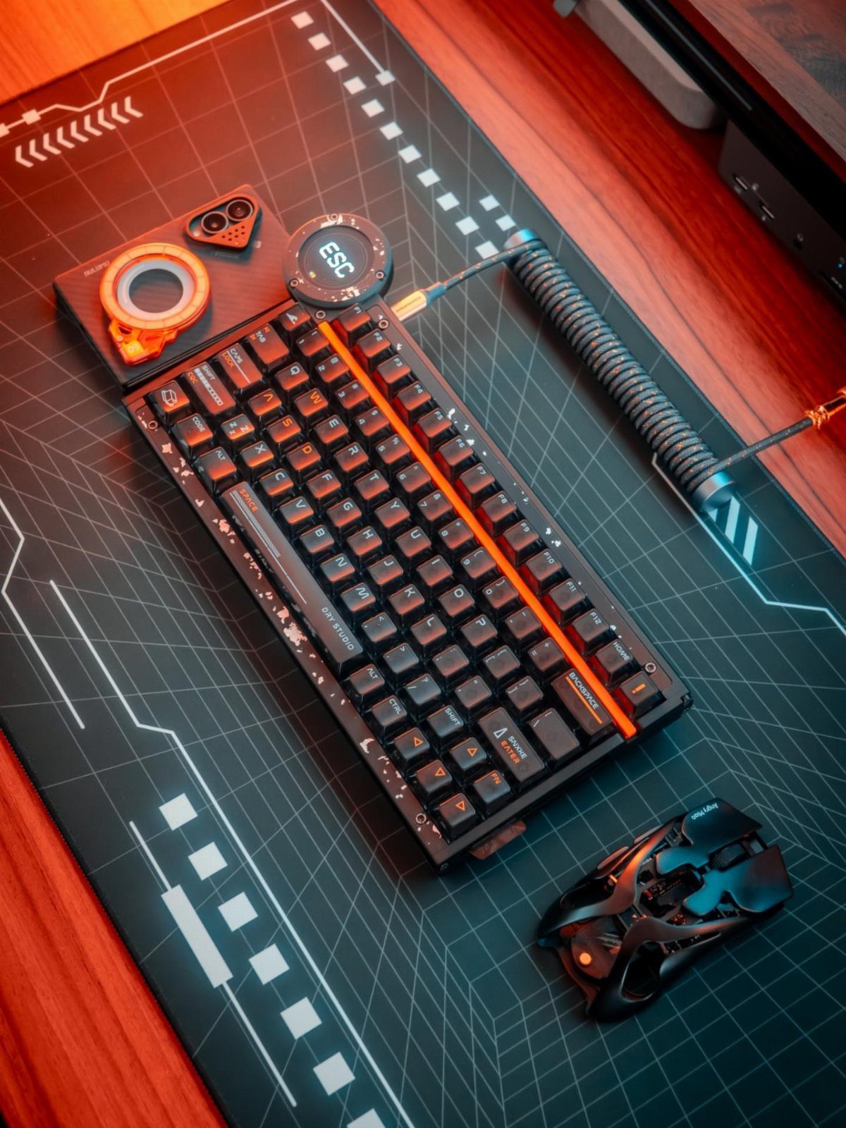 Mechanical keyboard and gaming mouse on a patterned mat over a wooden desk