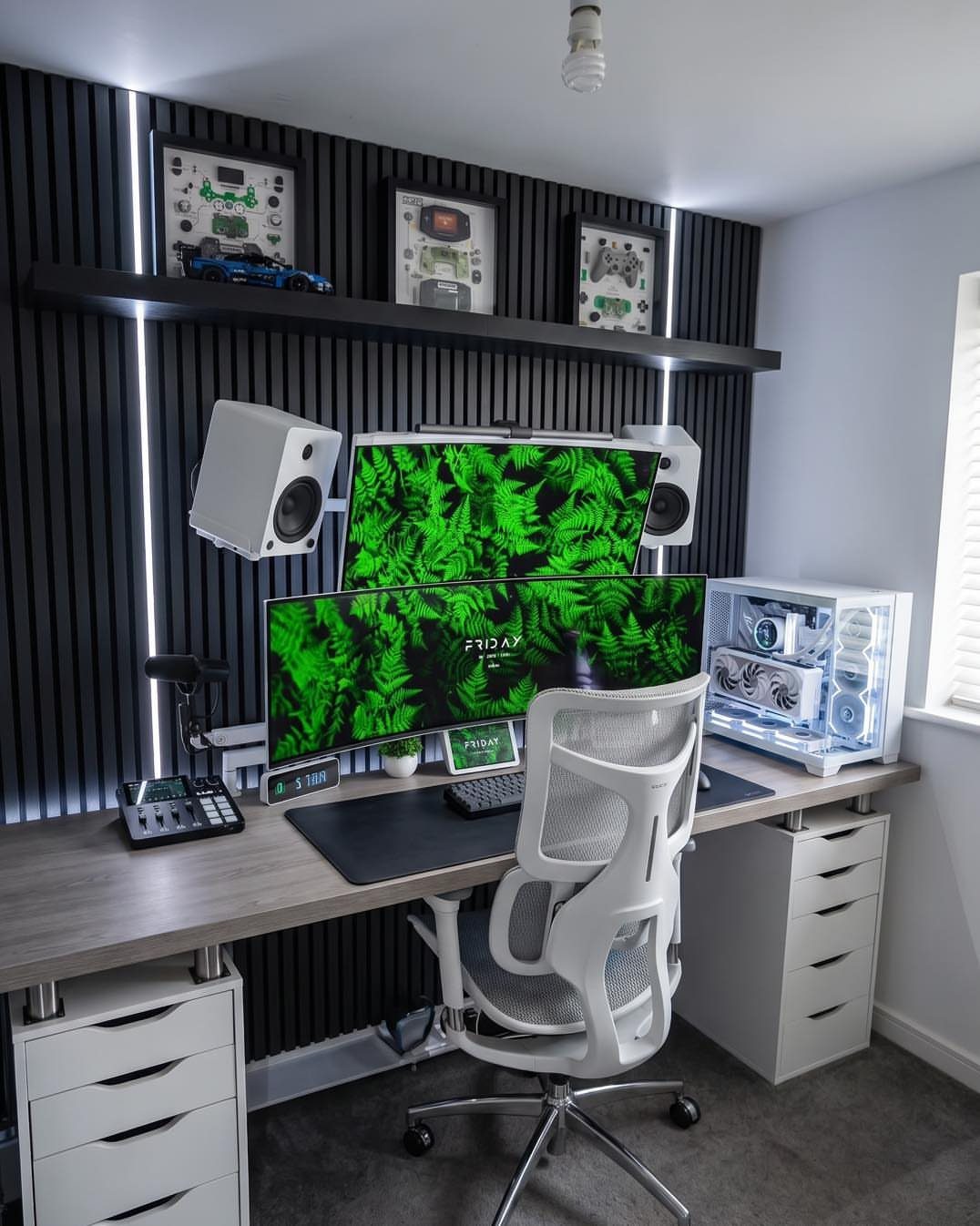 Two stacked monitors with green leaf wallpapers on a modern grey office desk.