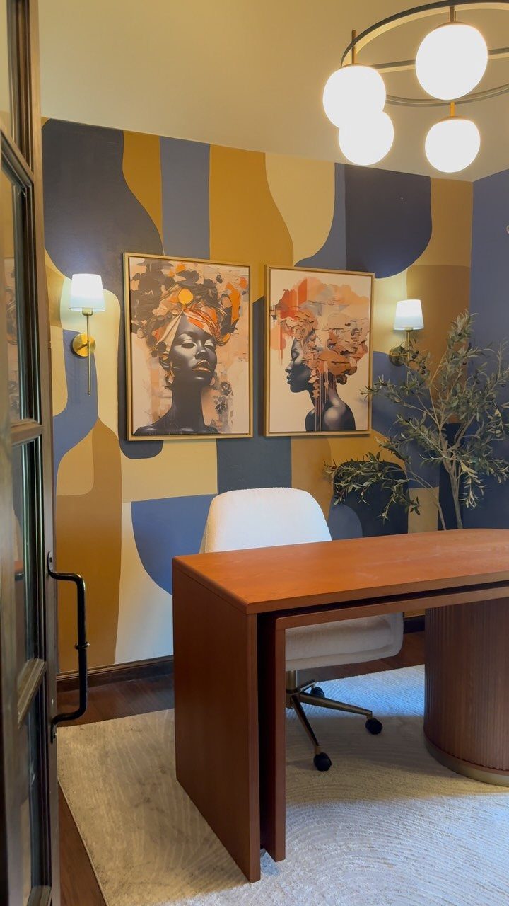 Home office with abstract blue and yellow painted walls, wooden desk, and art.