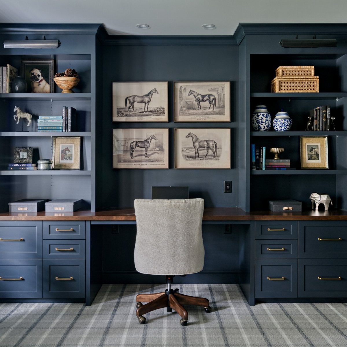 Deep blue home office walls with built-in shelving and a wooden desk.