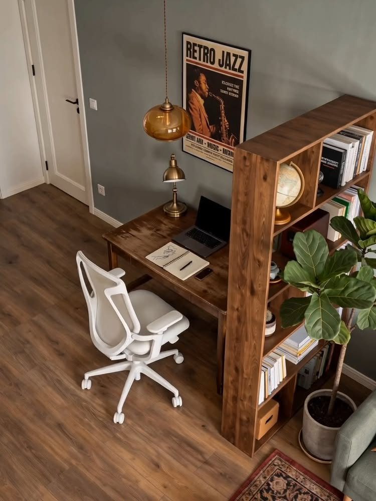 Home office with muted green walls, wooden desk, and white ergonomic chair.