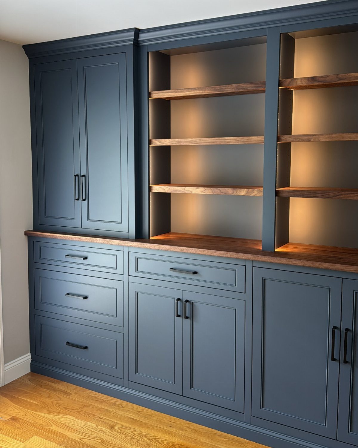 Blue built-in office cabinetry with warm wooden shelves and integrated lighting.