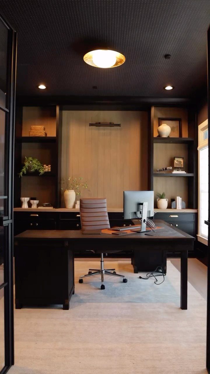 Home office with a dark desk, leather chair, and mixed carpet textures.