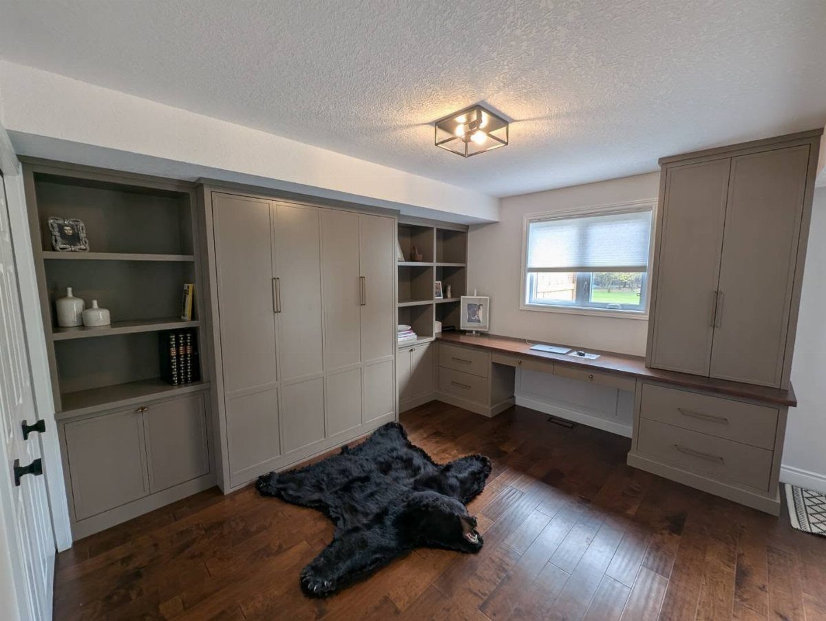 Grey built-in home office with a long corner desk and black hide rug.