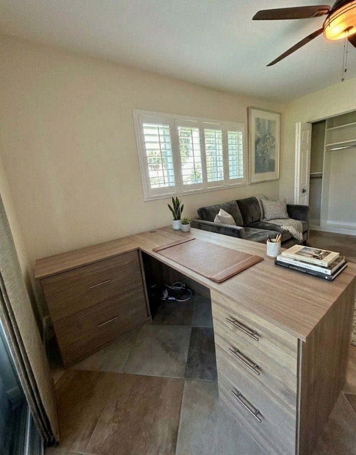 L-shaped light wood corner desk with drawers in a bright home office setting