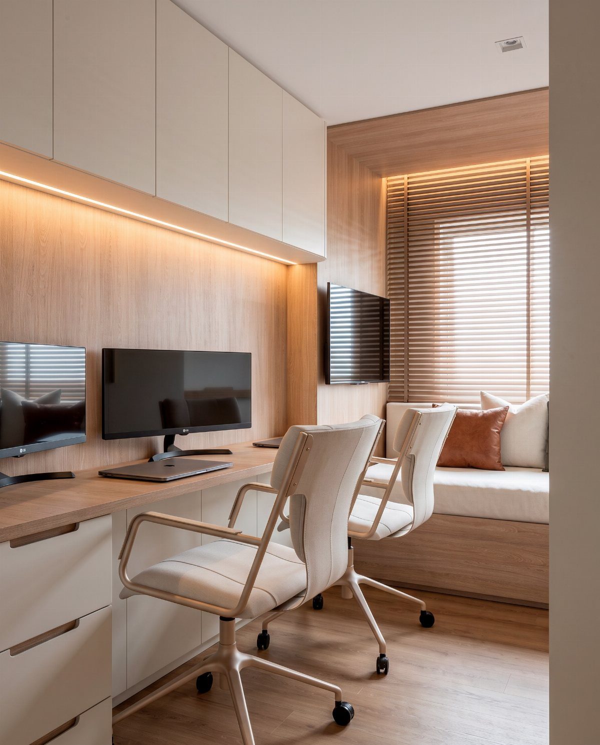 Modern home office with wooden desk, white chairs, and built-in window seat sofa.