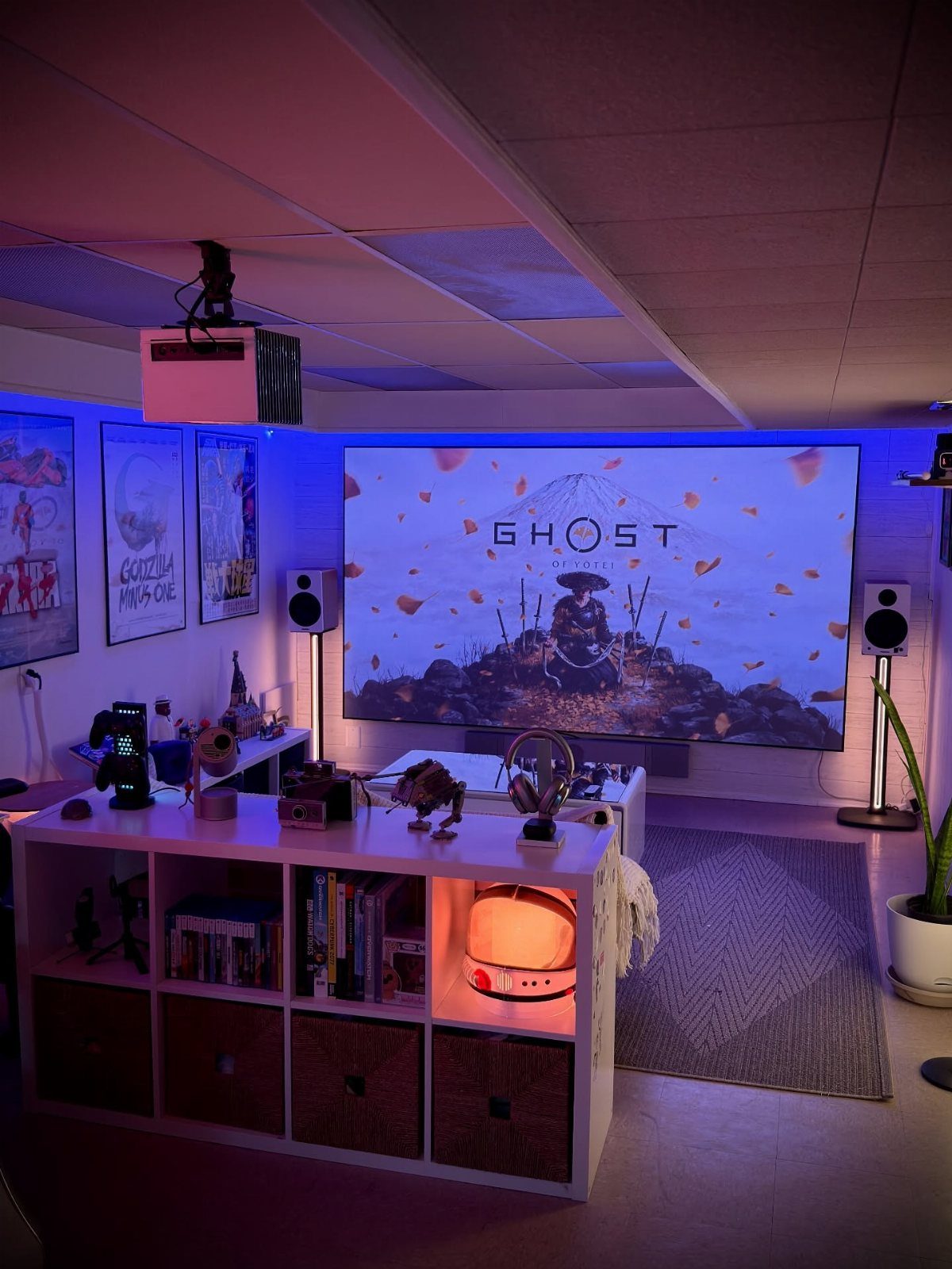 Gaming setup in a basement with a large screen and purple ambient lighting.