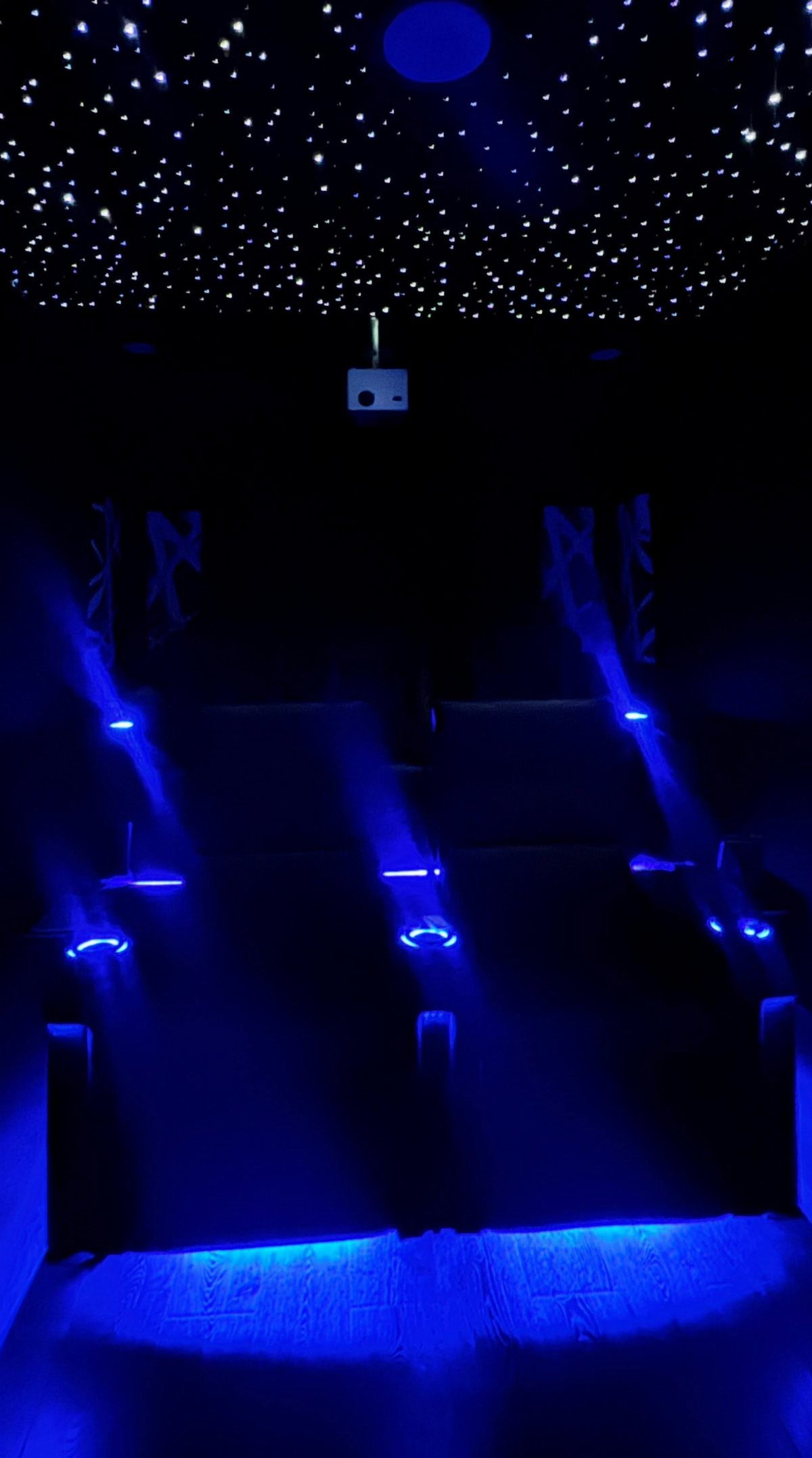 Starry night ceiling with twinkling lights and blue neon accents in a theater