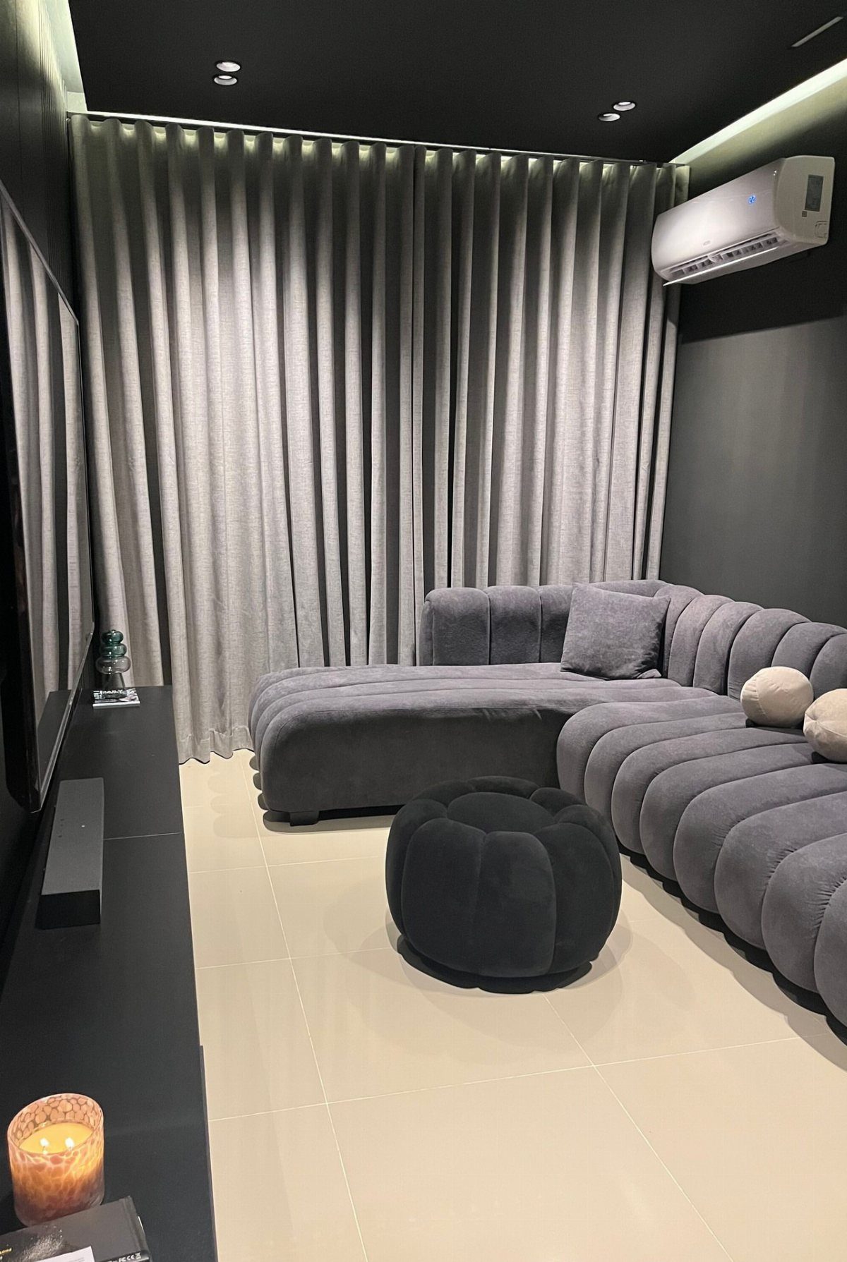 Grey pleated blackout curtains in a modern home theater with a modular sofa.