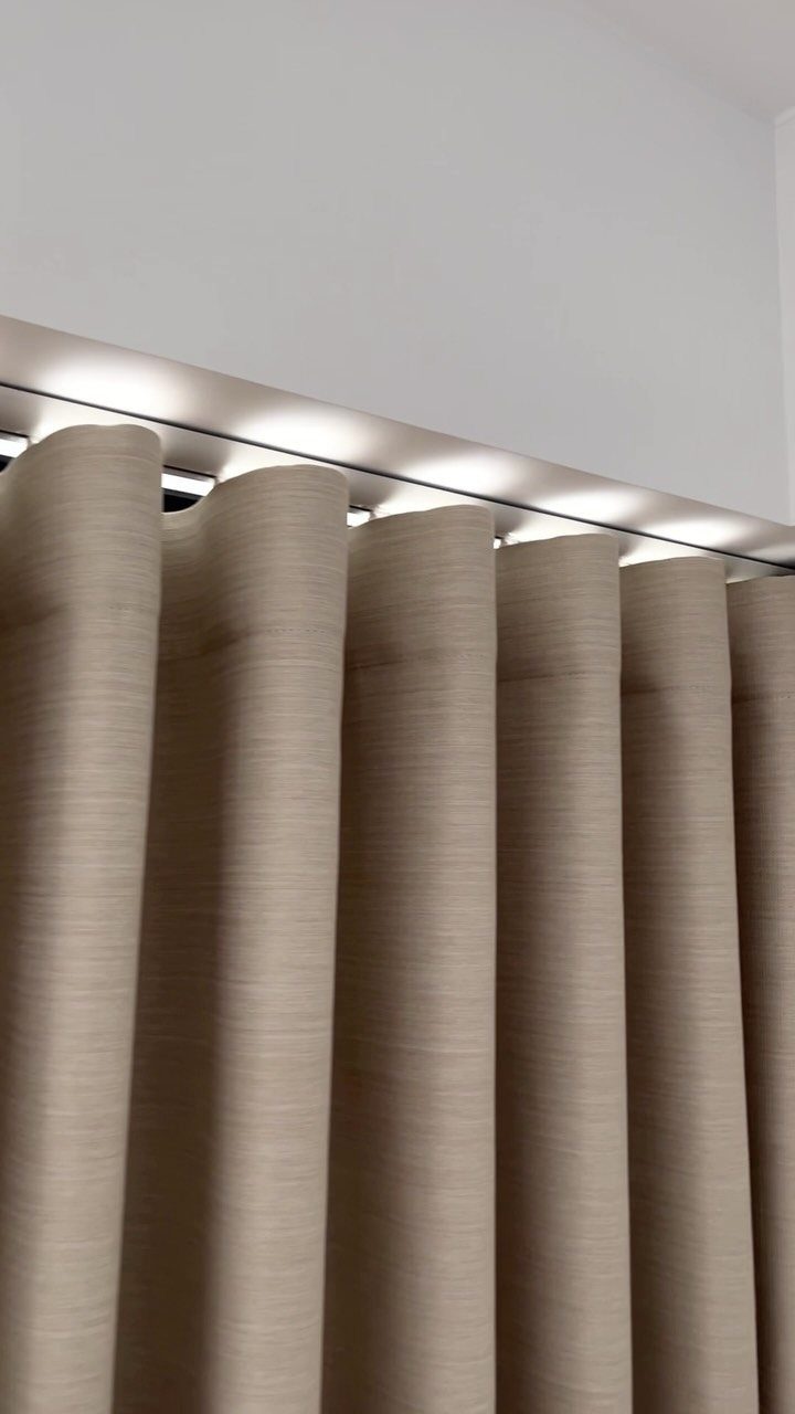 Beige blackout curtains with integrated LED strip lighting along the ceiling track.