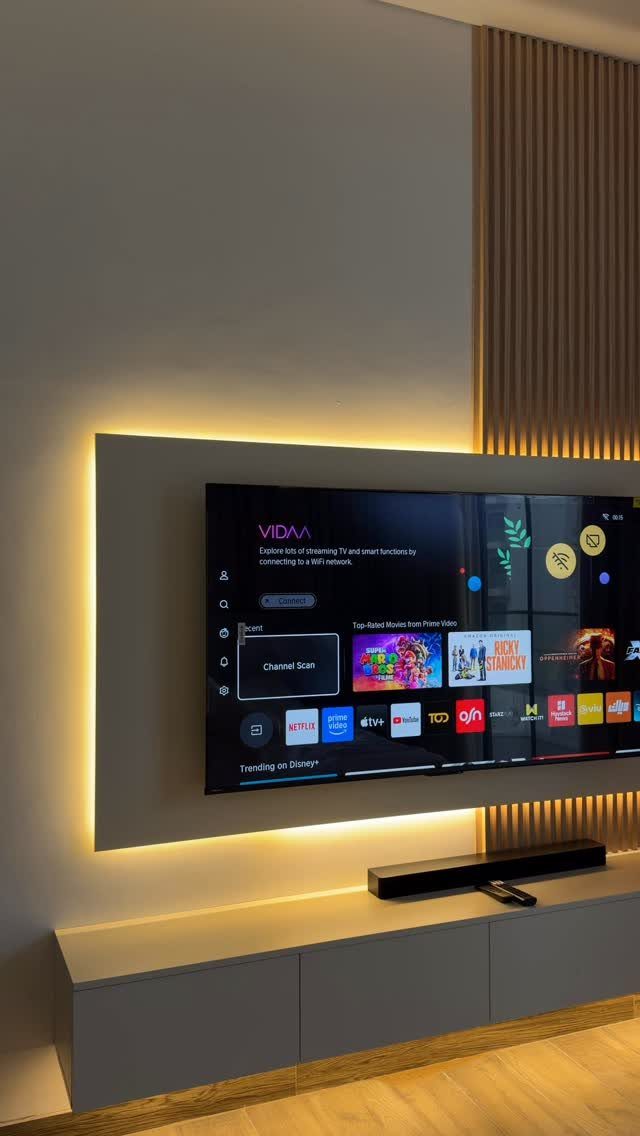 Mounted TV with warm backlight above a white cabinet and black soundbar.