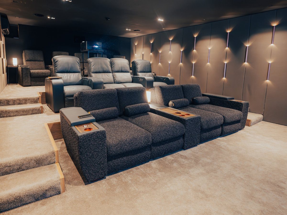 Plush reclining theater seats in a modern home cinema with accent wall lighting.