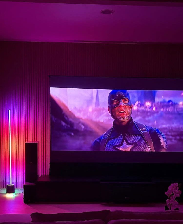 Home cinema room with a large projection screen and purple ambient lighting.