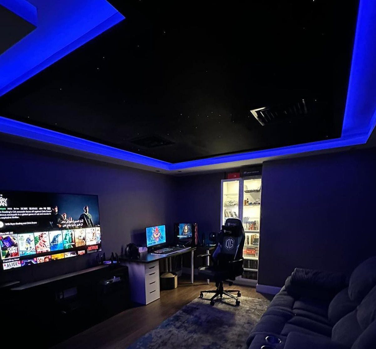 Home movie and gaming room with blue LED lighting, large TV, and sofa.