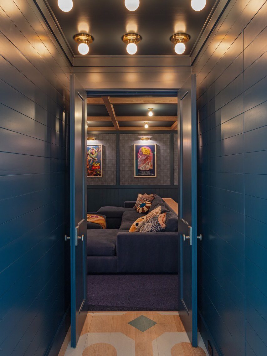 Navy blue media room with a large sectional sofa viewed through open doors.
