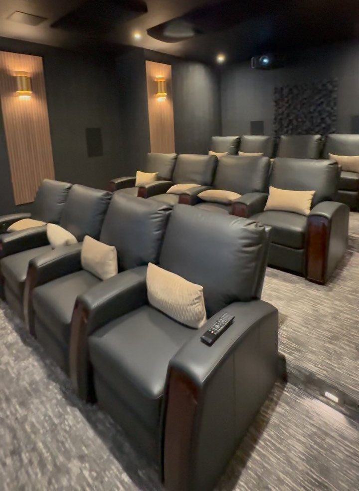 Grey leather reclining cinema seats in a dark home movie room with sconce lighting