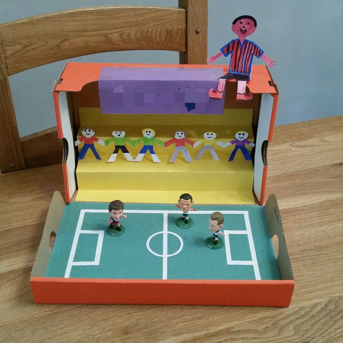 Homemade table football game made from a cardboard box with small plastic players.