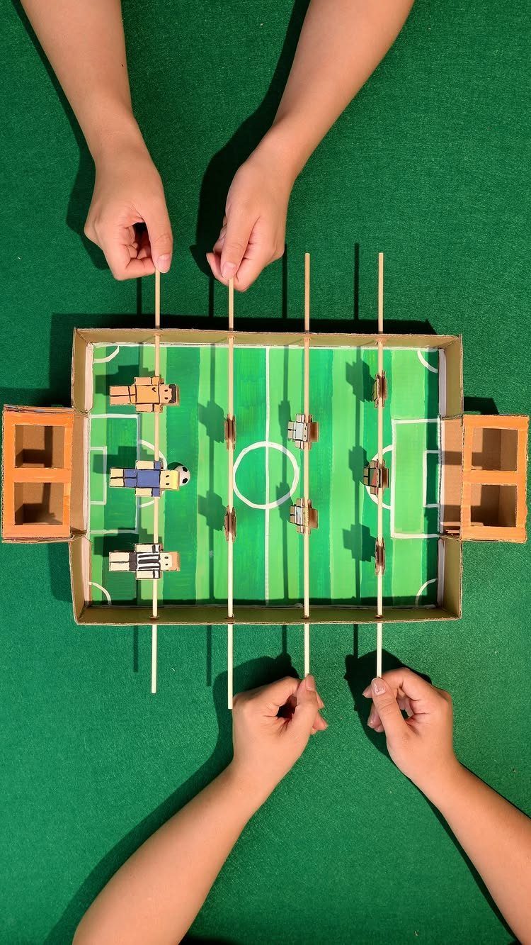 Homemade table football game made from a shoe box and wooden dowels.