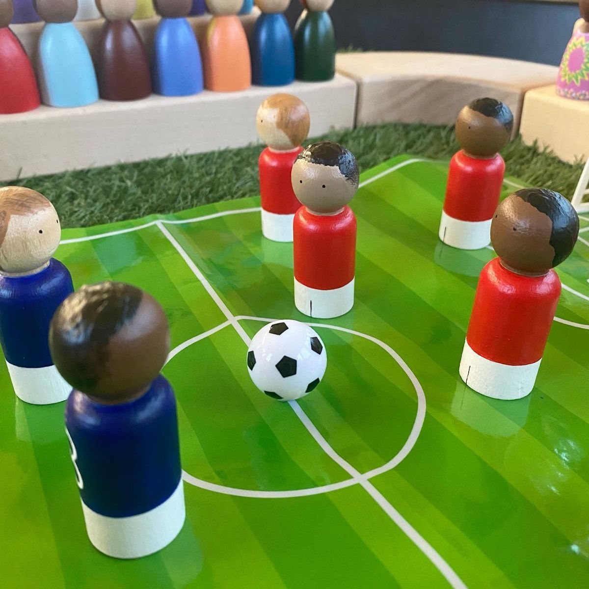 Wooden peg figures painted as football players on a green game board.