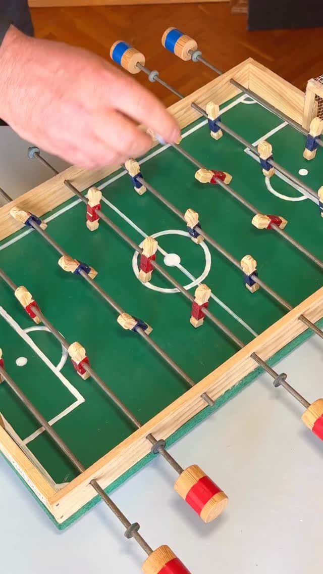 Homemade table football game with wooden players and a green playing field.