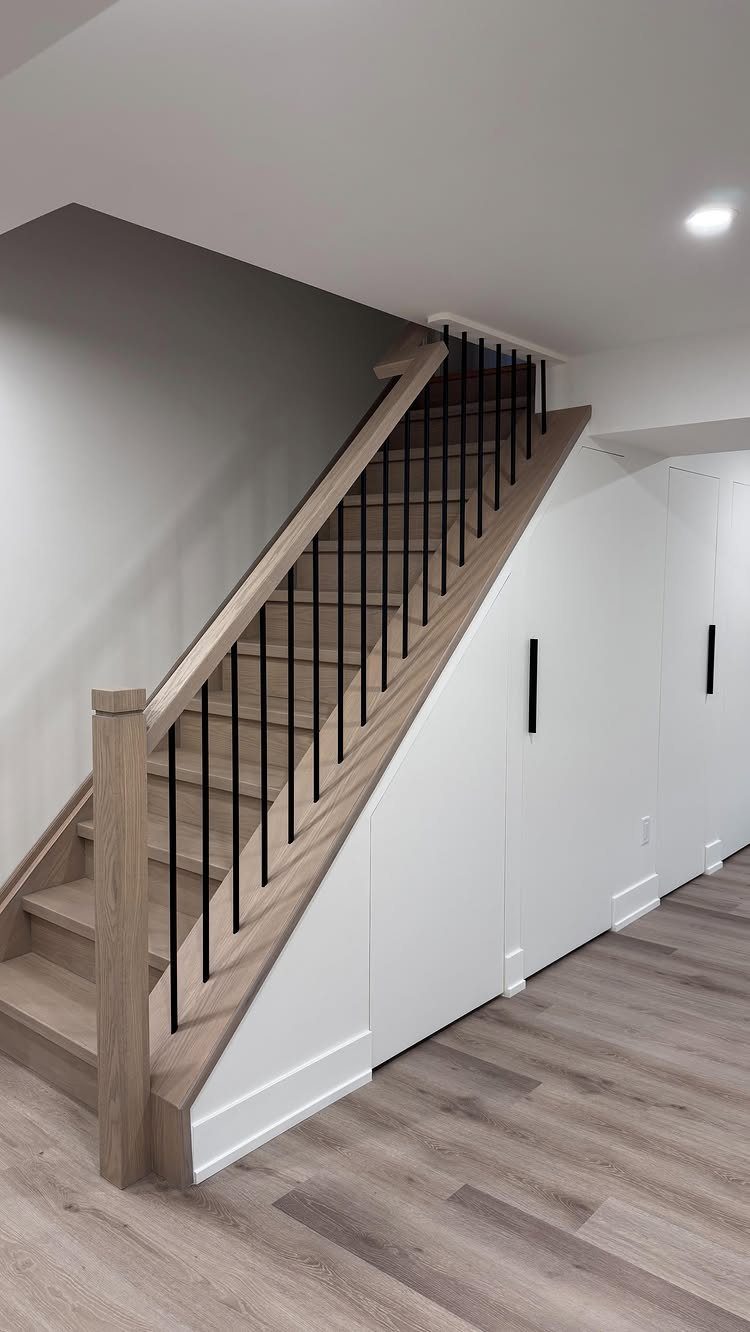 Wooden stairs with built-in white storage cabinets installed in the space underneath.