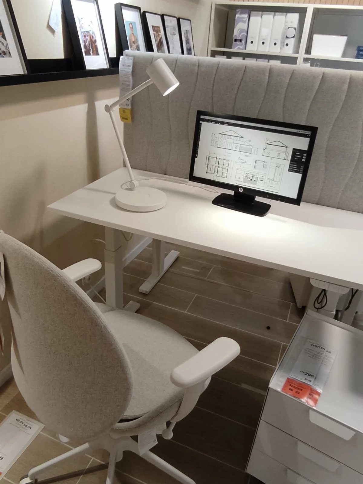 White office desk with a grey fabric acoustic screen and a desk lamp.