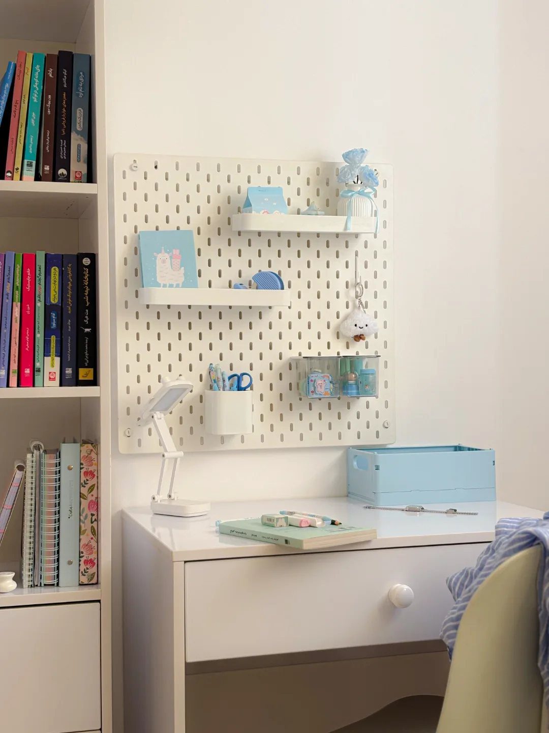 White desk and wall-mounted pegboard with organizers in a small home office space.