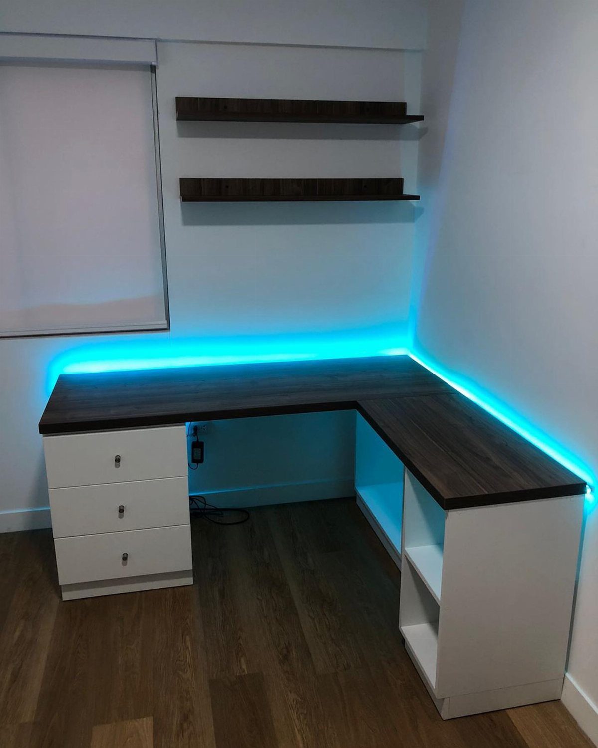 L-shaped desk with dark wood top, white base, and blue LED backlight.