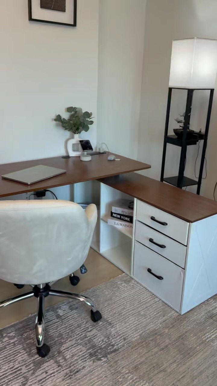 L-shaped desk with brown top and white drawers next to a white office chair