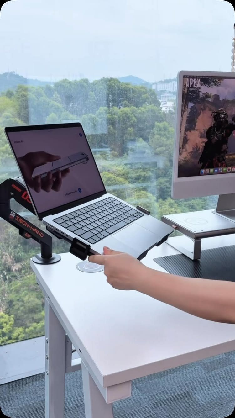 Laptop on a black stand and monitor on a riser on white desk