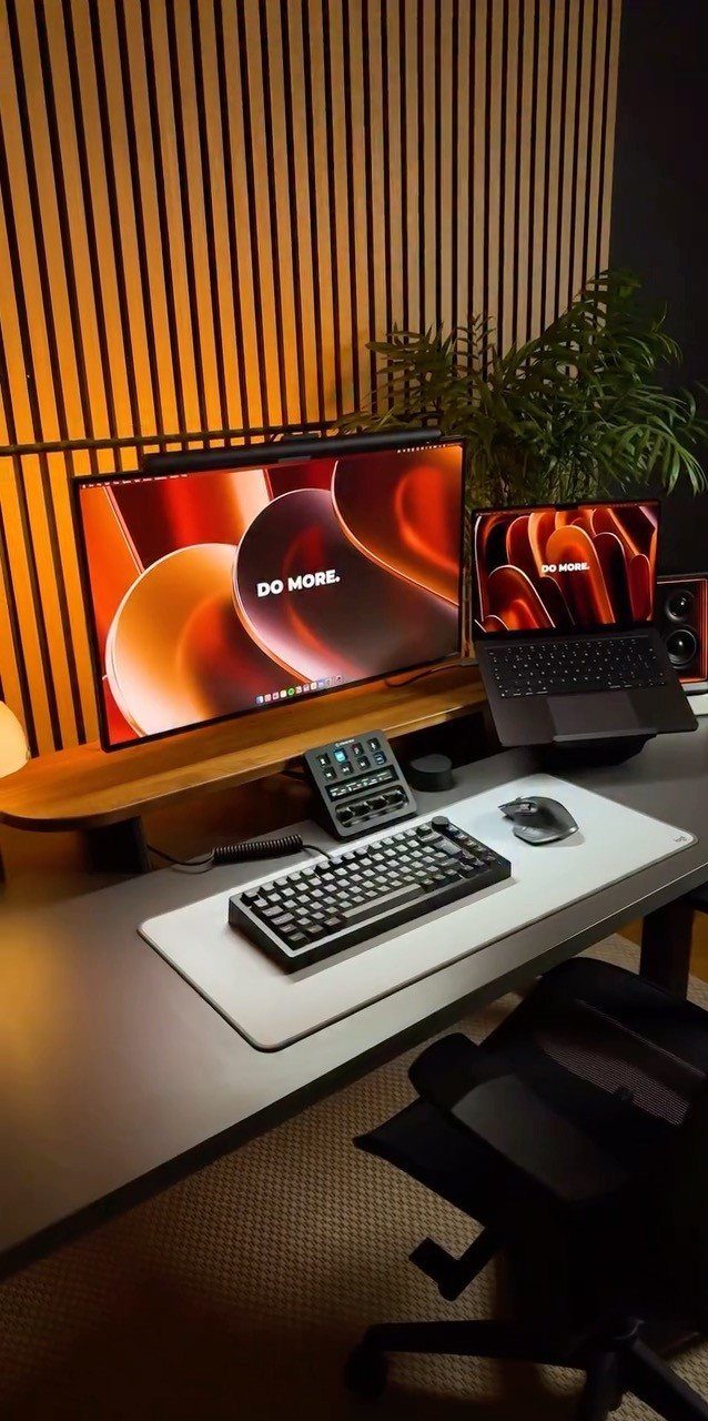 Laptop and monitor desk setup with mechanical keyboard on a white desk mat.