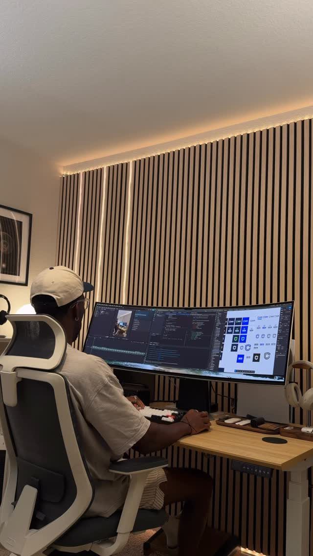 Person sitting at a wooden desk using a large curved ultrawide monitor