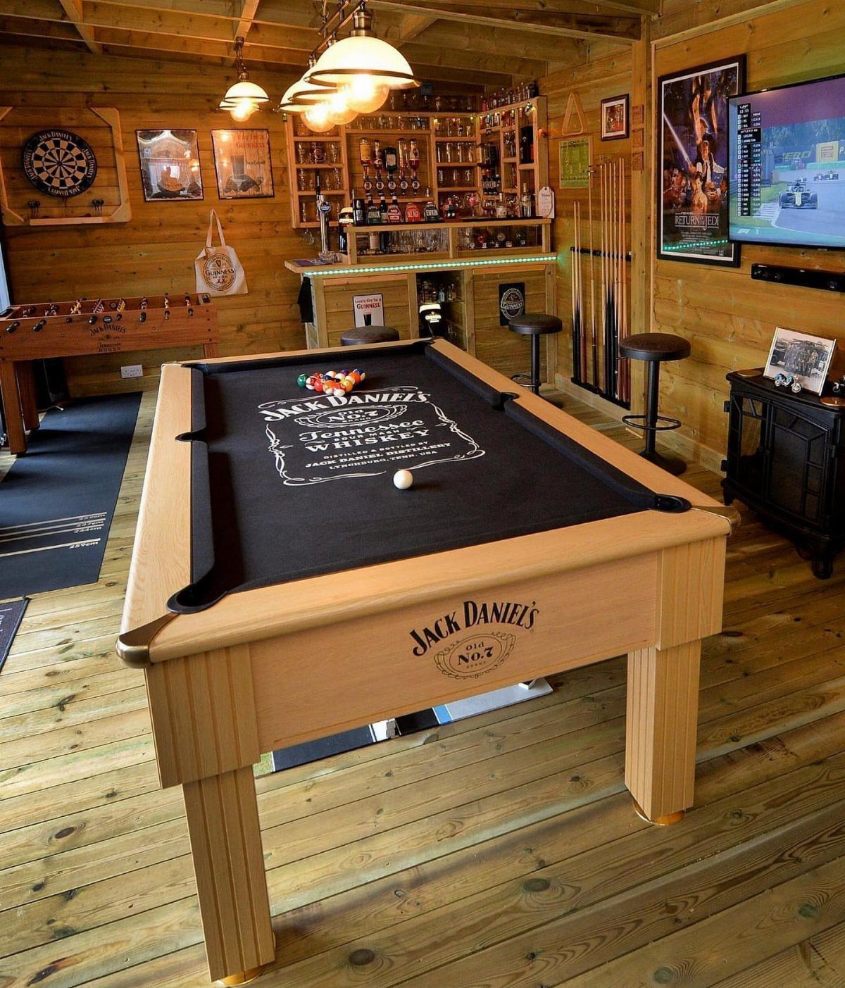 Pool table and home bar in a wooden game room with foosball table