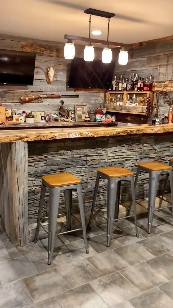 Rustic home bar with live-edge wood counter, stone facing, and reclaimed wood walls.