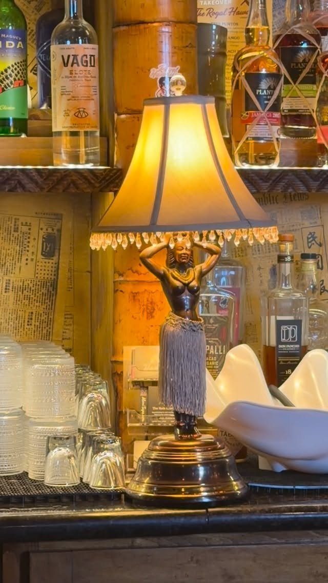 Hula girl lamp on a bar counter with liquor bottles and bamboo walls