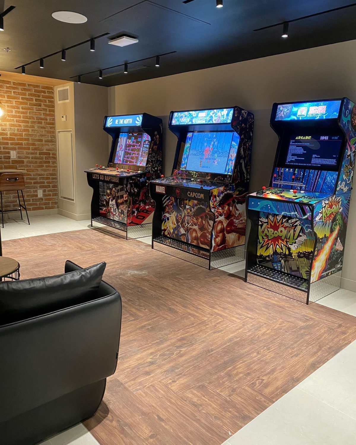 Three colorful retro arcade game cabinets standing in a modern game room.