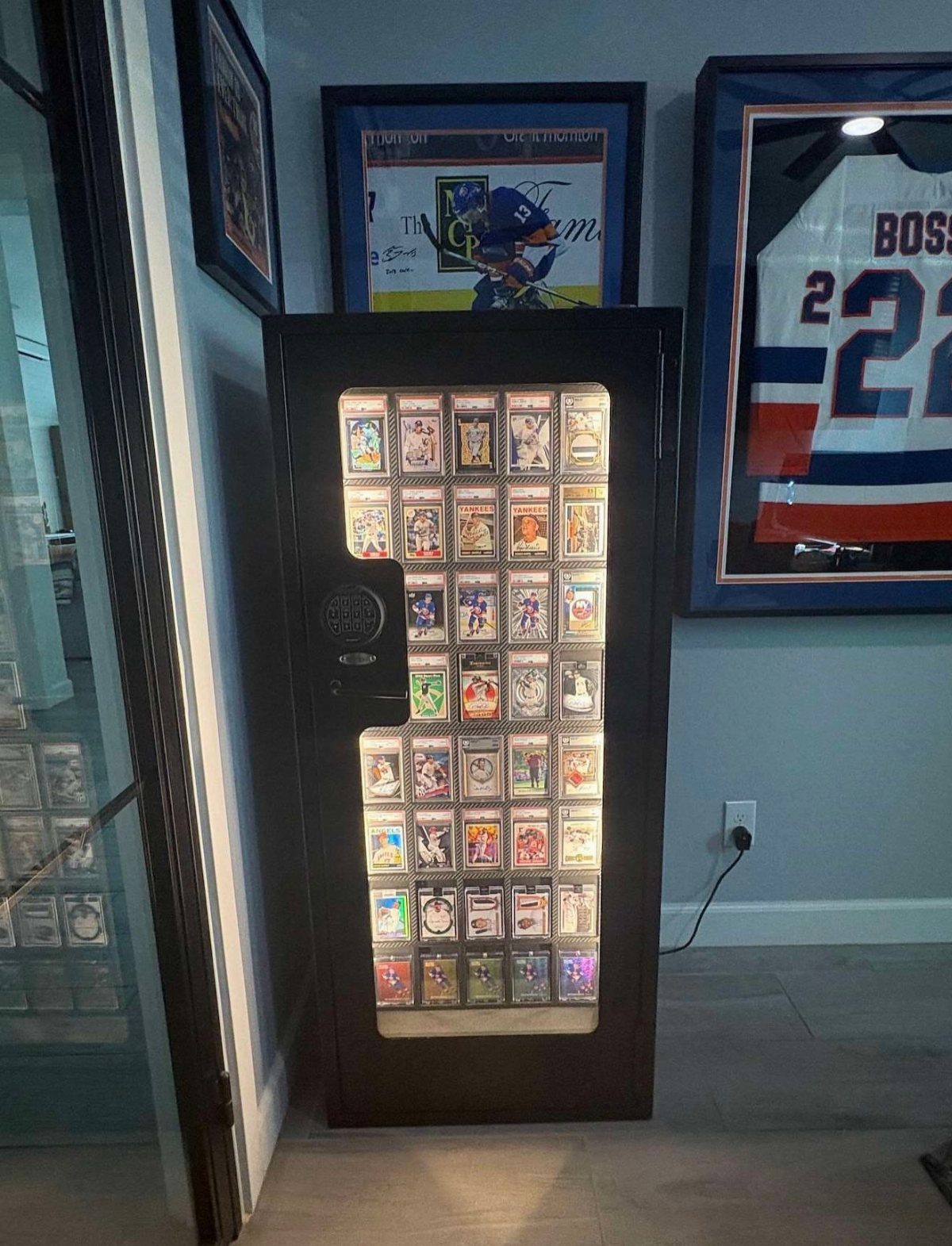 Illuminated black display case showcasing a collection of graded sports trading cards.