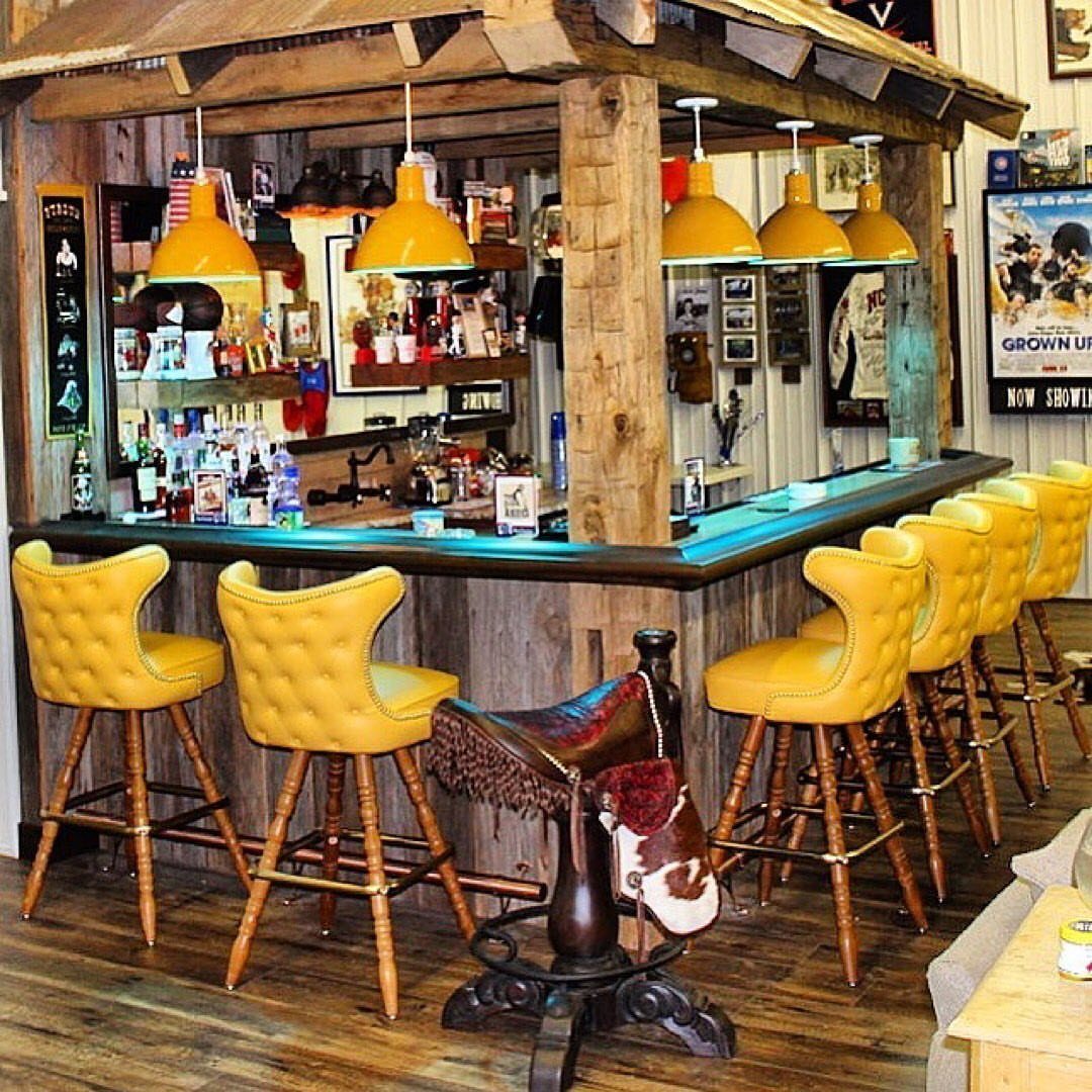 Yellow tufted leather bar stools lined up at a rustic wooden home bar.
