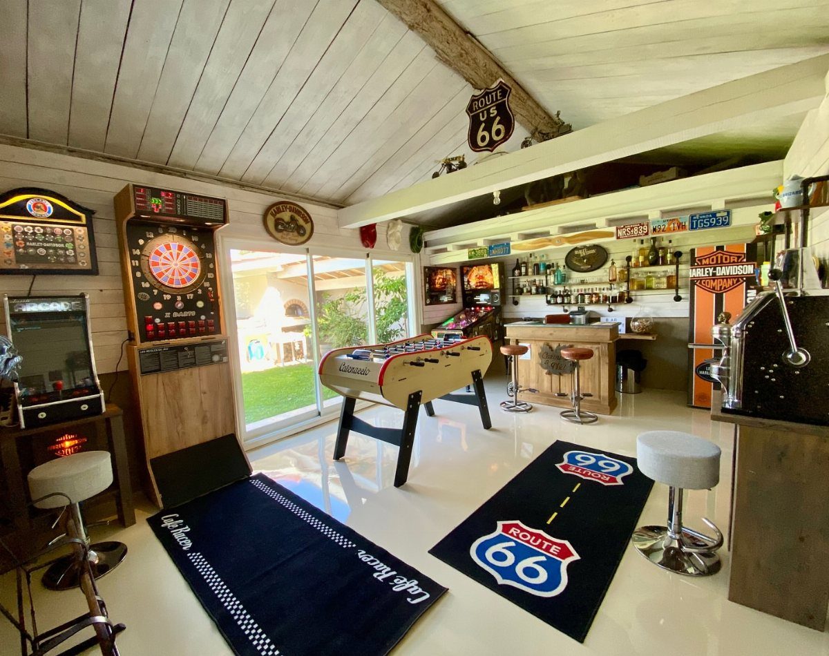 Man cave interior with foosball table, dartboard, bar stools, and Route 66 decor.
