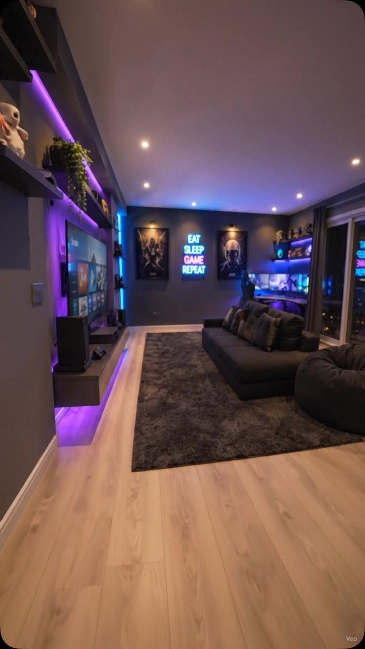 Modern gaming room with purple LED lighting, grey sectional sofa, and PC setup.