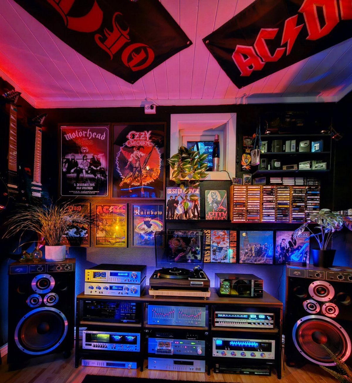 High-end audio system with large speakers and amplifiers in a rock-themed room.