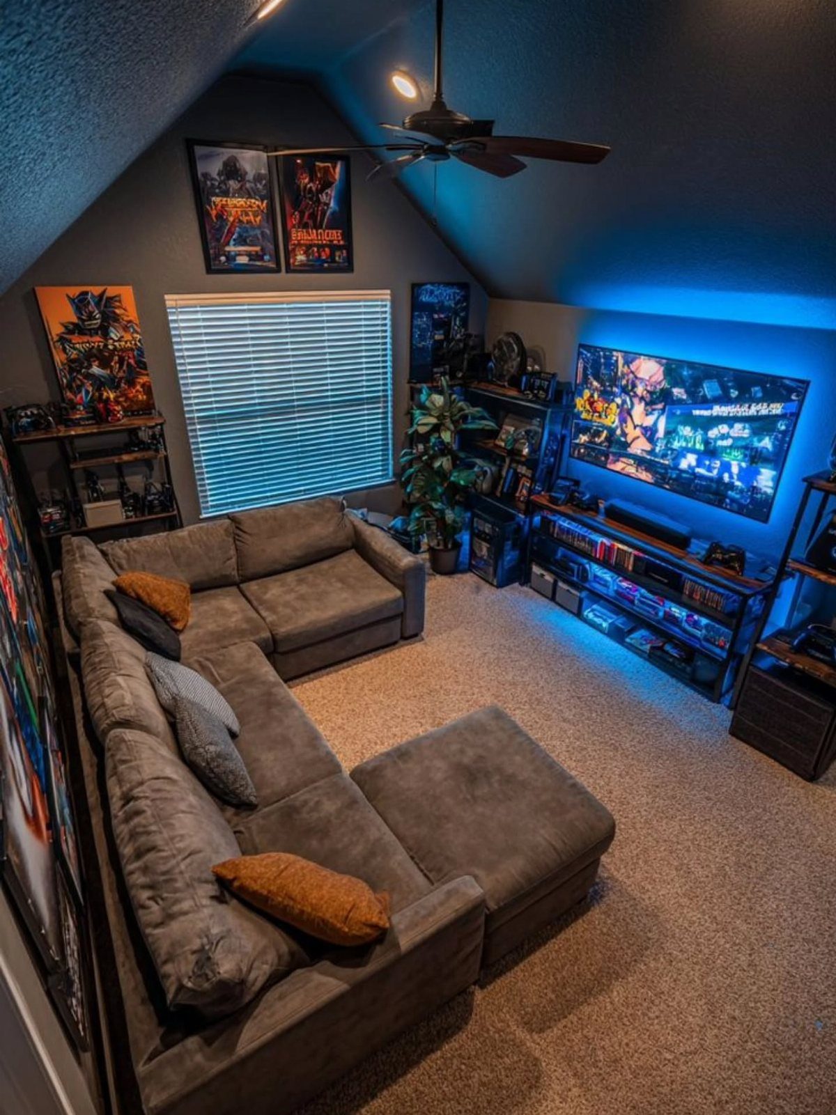 Gaming room with a grey sectional sofa, large TV, and blue ambient lighting.