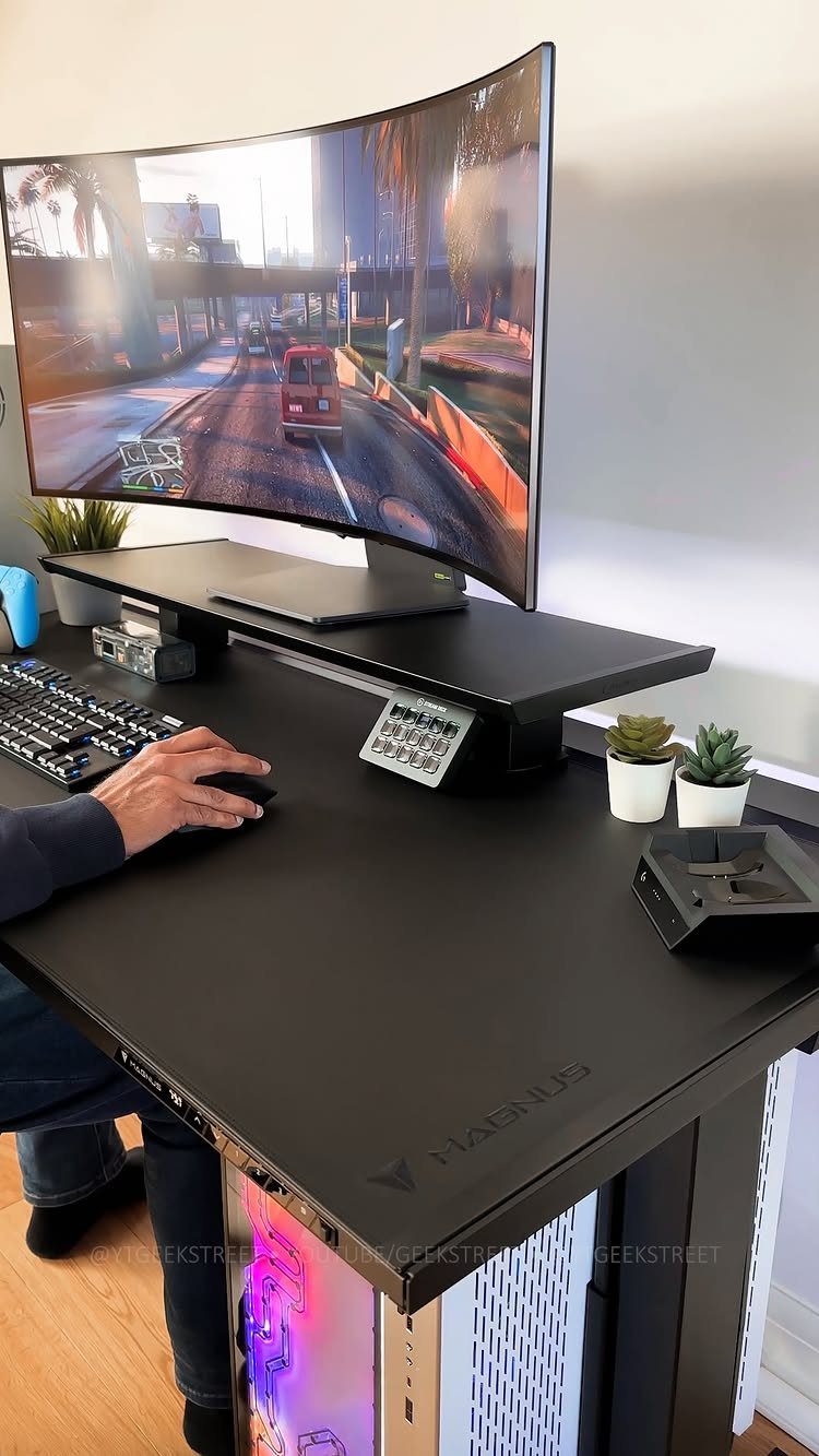 Curved gaming monitor and black desk setup with a person using a mouse.