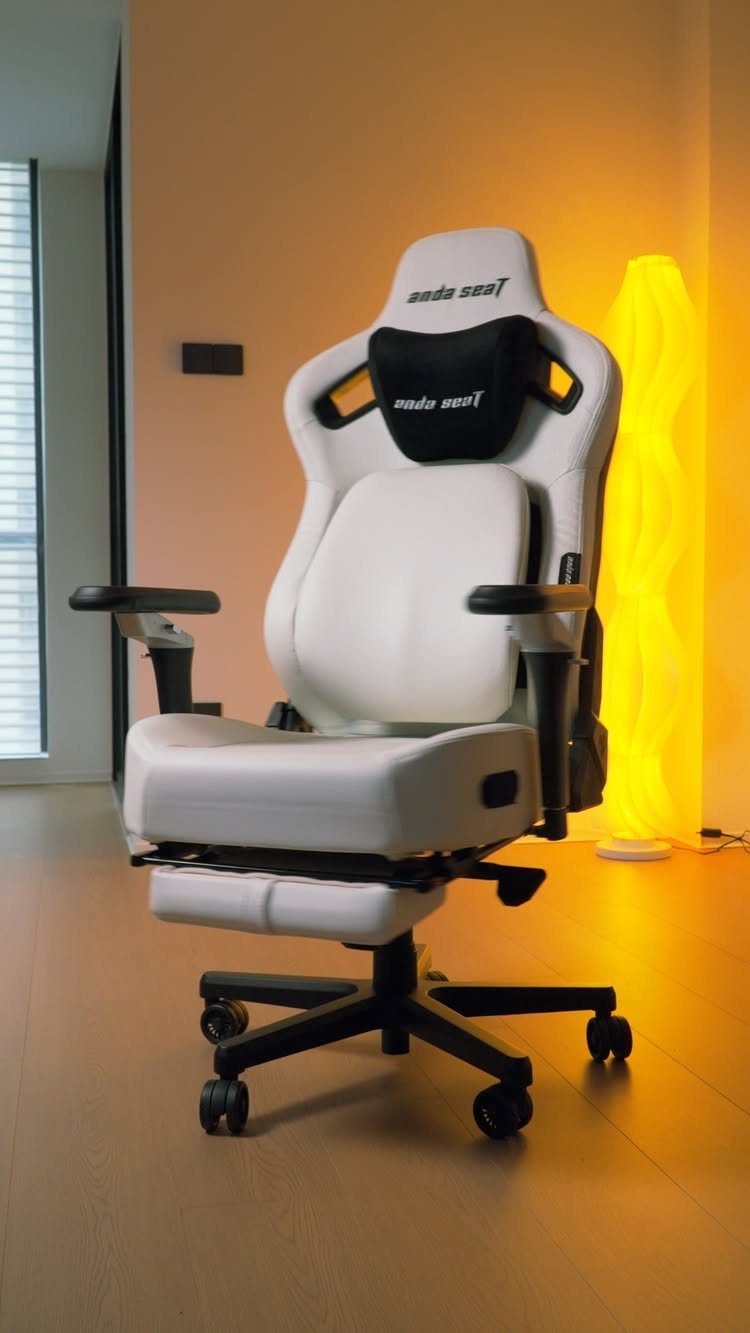 White and black ergonomic gaming chair next to a glowing yellow floor lamp.