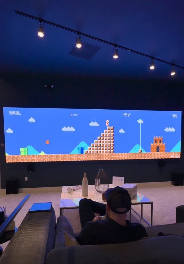 Man watching Super Mario Bros on a large projection screen in a dark room