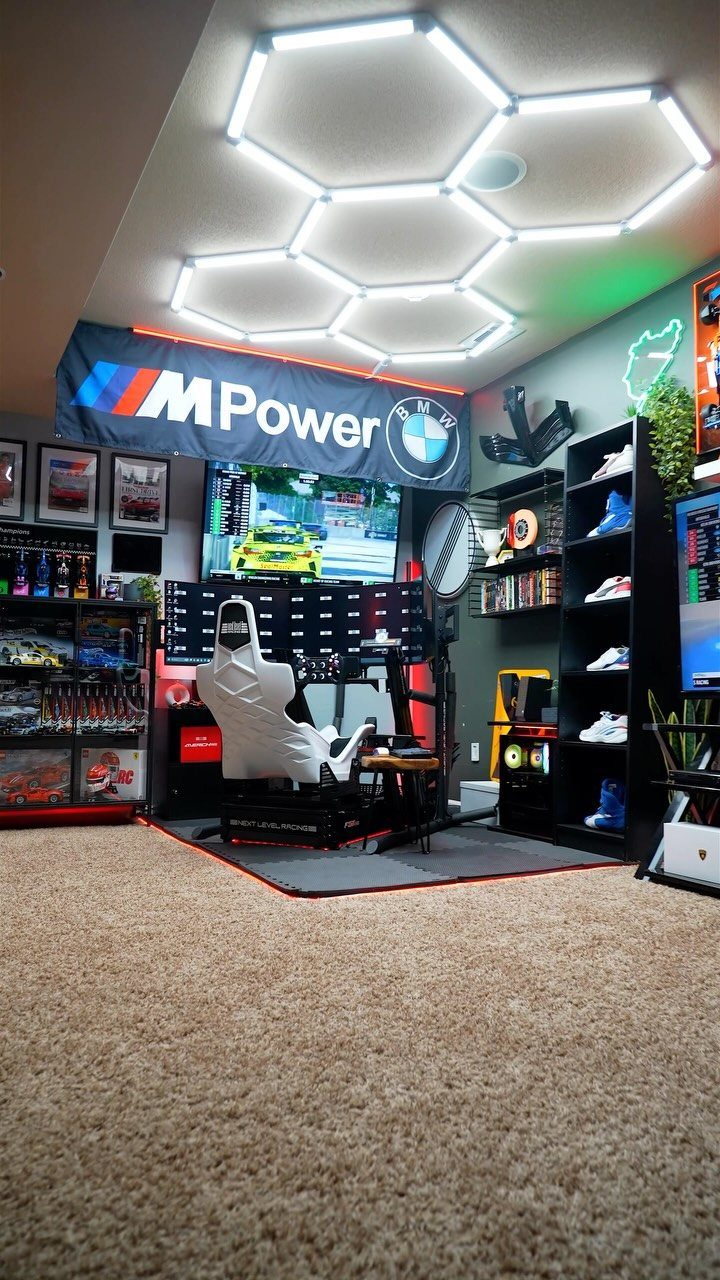 Racing simulator setup in a game room with hexagonal ceiling lights and BMW decor.