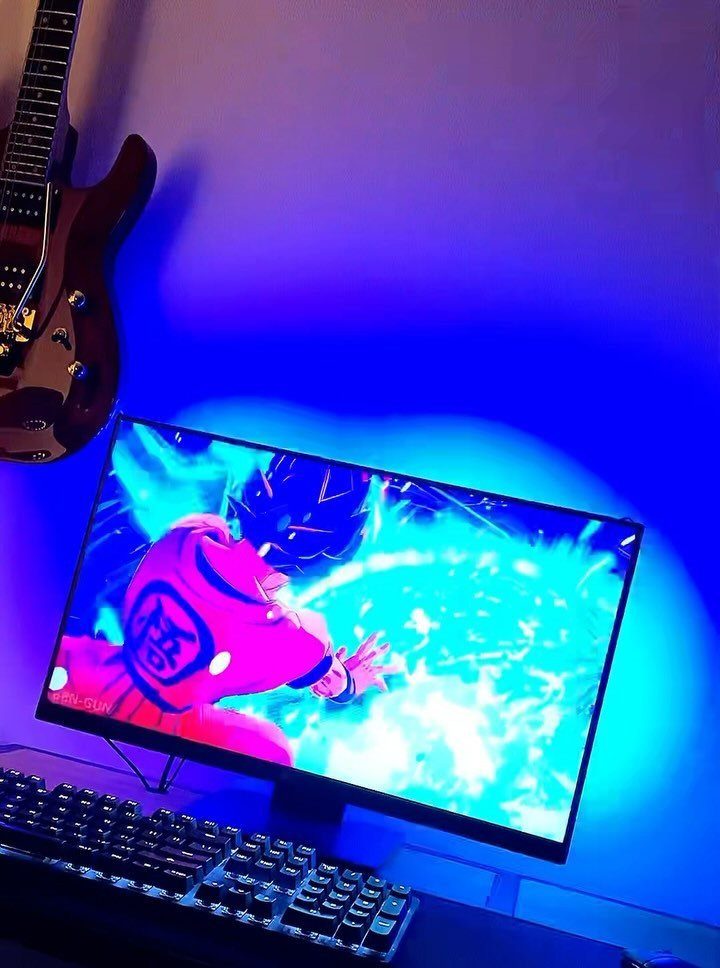 Computer monitor with anime art and blue purple RGB lighting on the wall